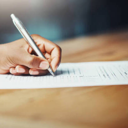 a hand holding a pen, filling out a form